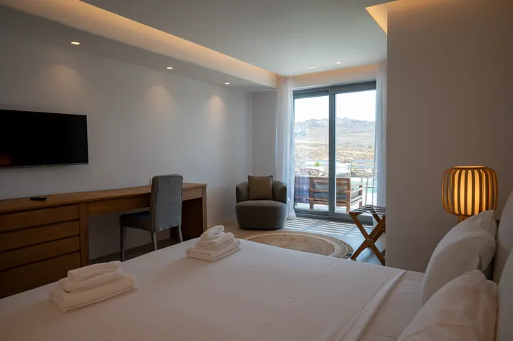 Modern bedroom with balcony, mountain views, and cozy seating